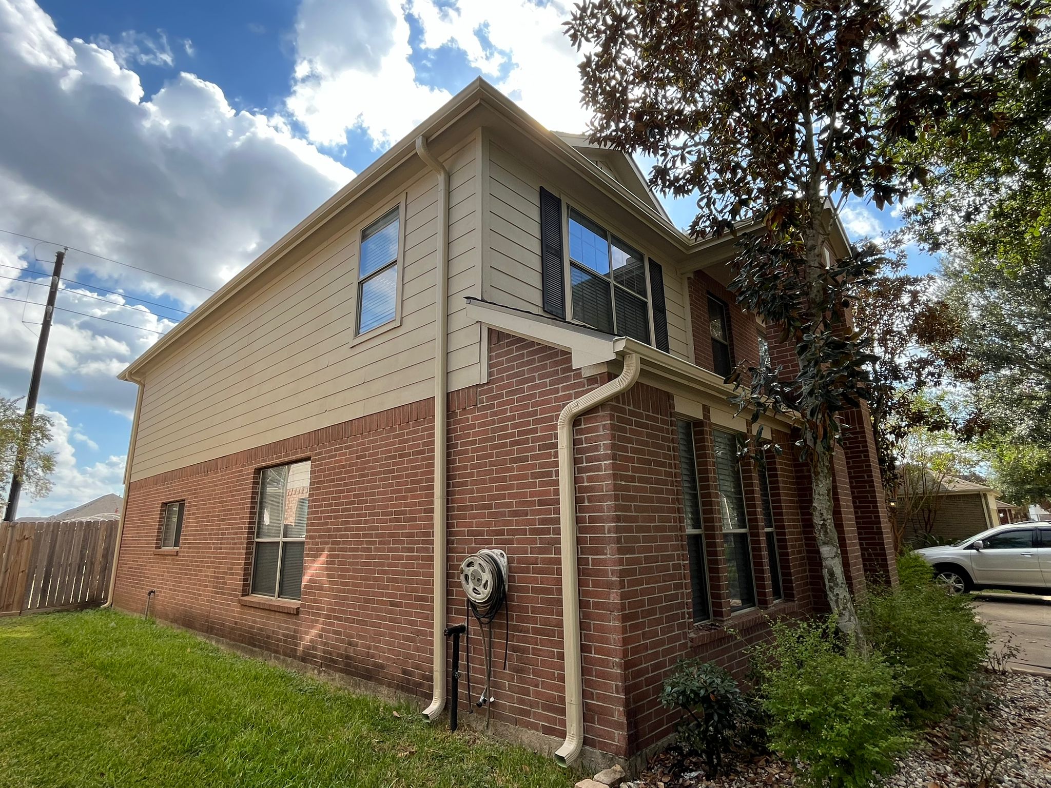 Two-story brick home with white seamless downspout