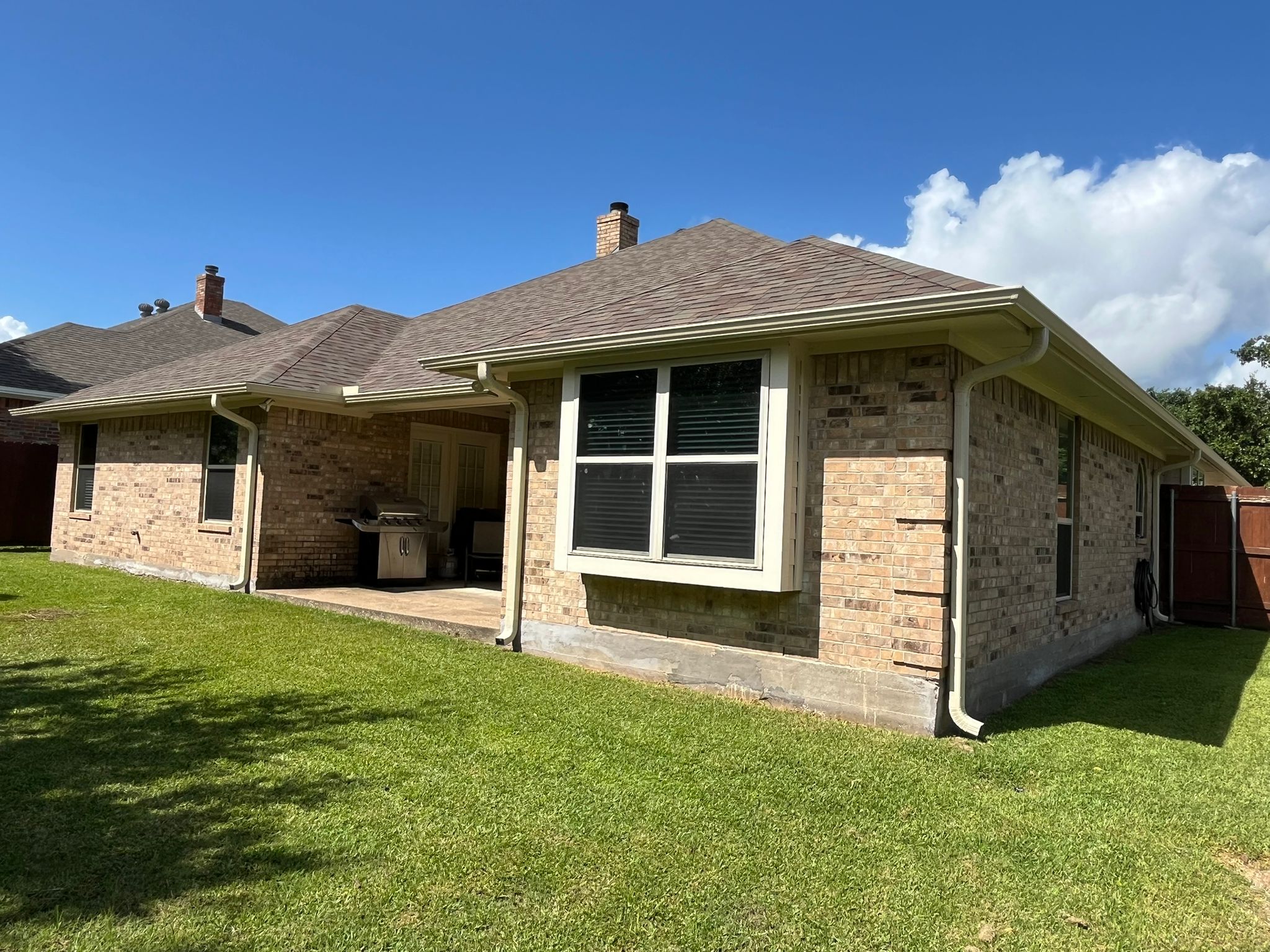 Brick home with white seamless gutters after installation