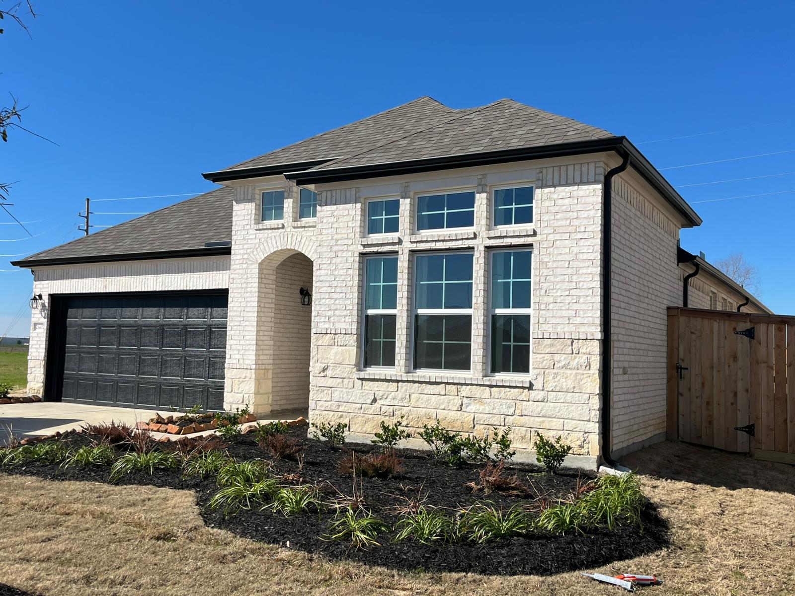 White brick Houston-area home with black seamless gutters and downspout