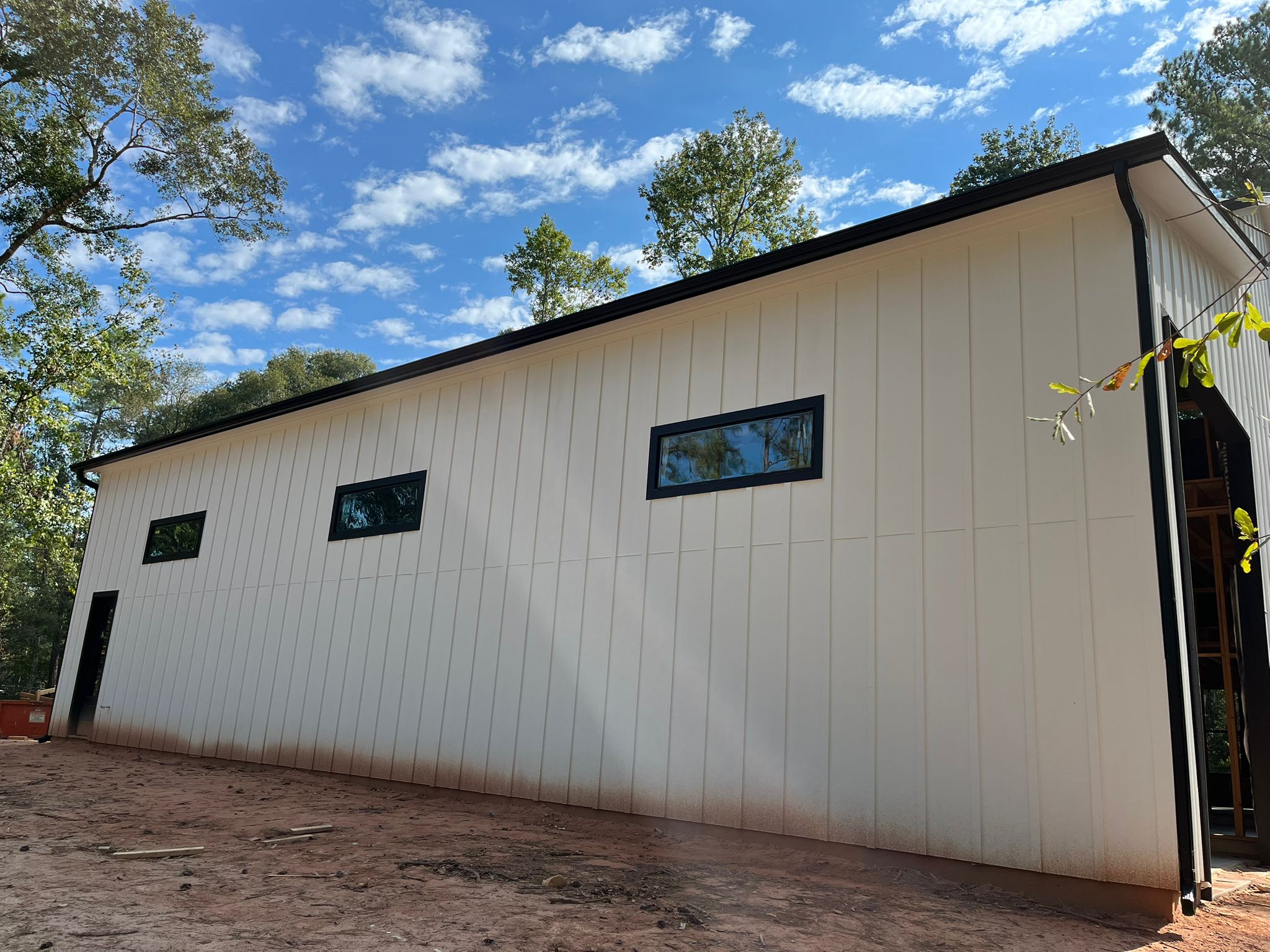 White board-and-batten building with black seamless gutters