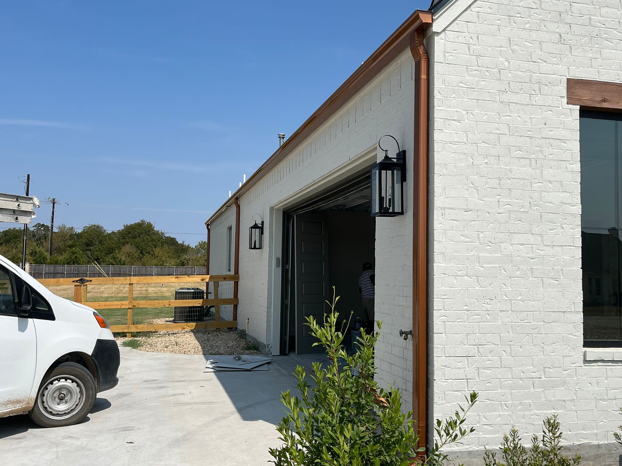 Copper downspout on a white brick home