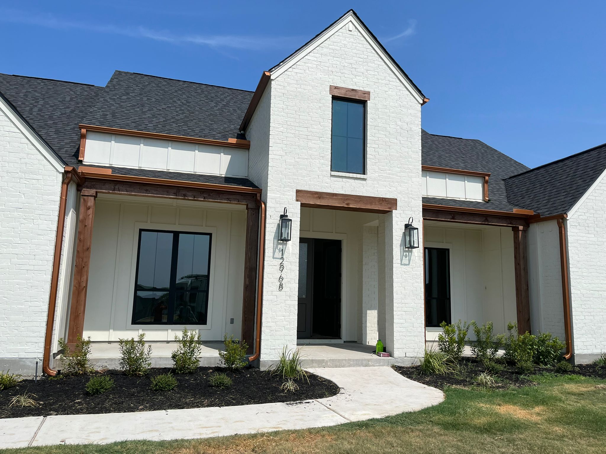 Finished white brick home with copper gutters and downspouts