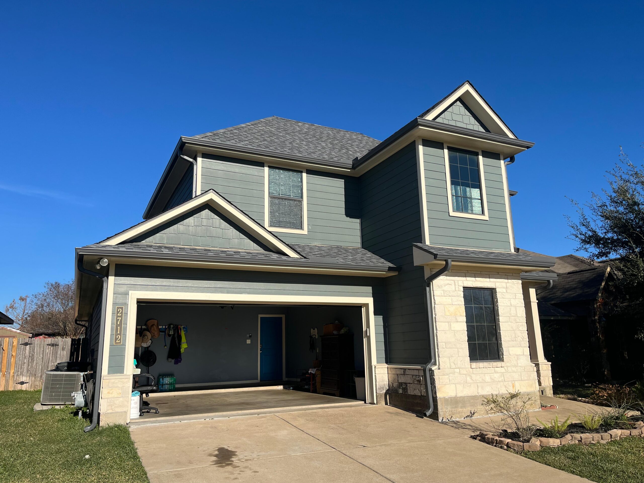 Two-story home with seamless gutters and an open garage