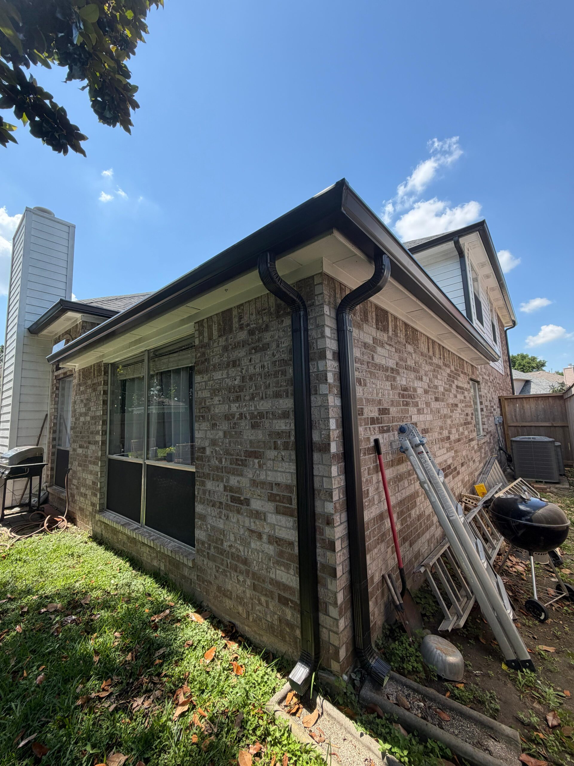 Black seamless gutter and downspout on a brick home
